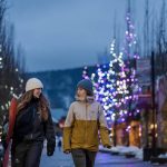 Two snowboarders in conversation walking through Whistler village at night.