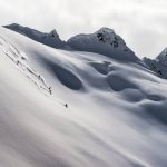 Group of heli-skiers descending on a slope near Mica Heli Skiing Lodge.