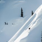 Heli-skier riding down a steep slope near Mica Heli Skiing Lodge.