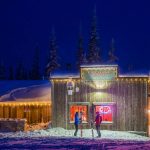 Two skiers conversing in front of a shop in the snow at SilverStar.