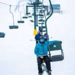 Skier sitting on the Silver King chairlift at Whitewater Ski Resort.